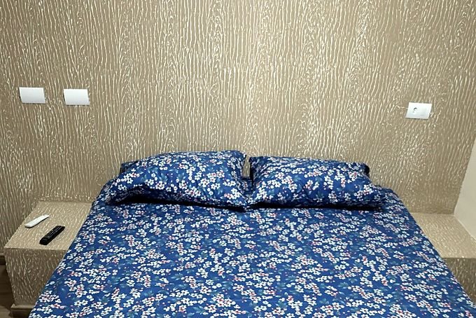 Cama de casal do Hotel Costa com cabeceira de papel de parede e mesa de apoio