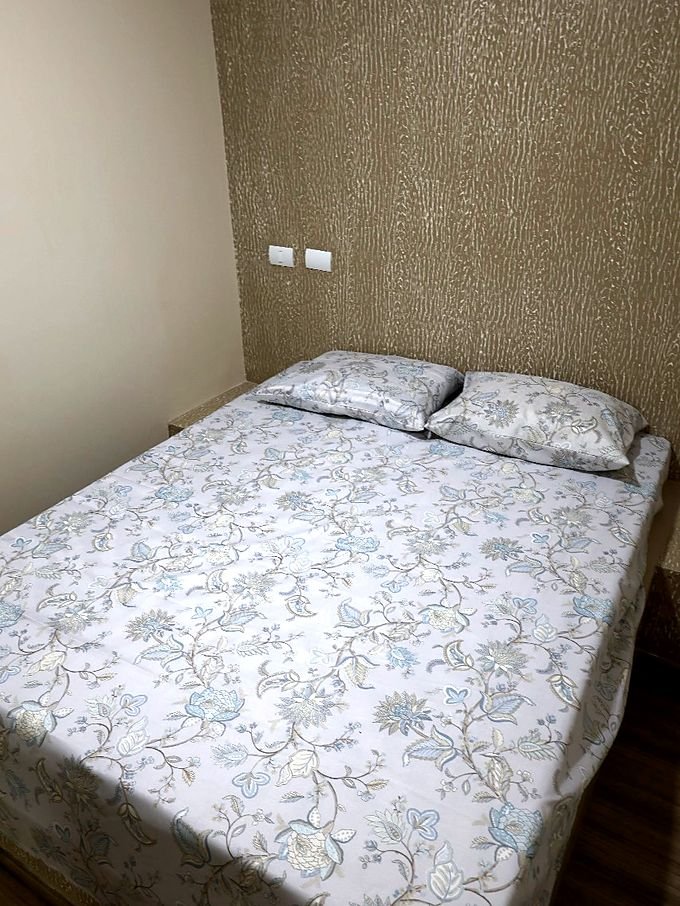 Quarto de casal do Hotel Costa com colcha clara e cabeceira de papel de parede