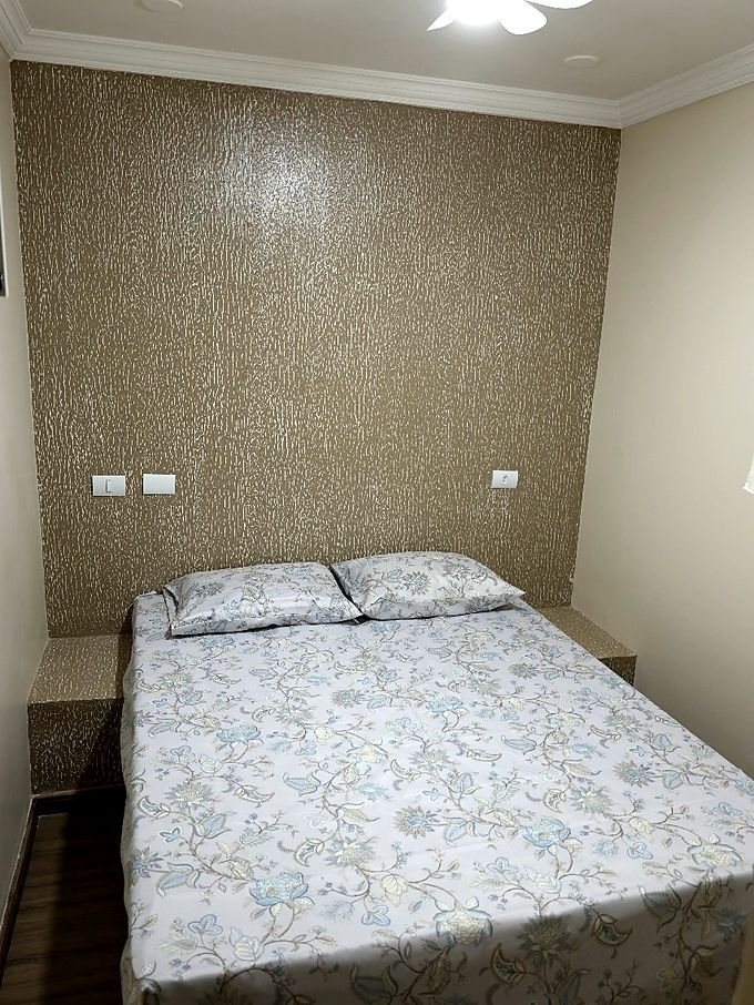Quarto do Hotel Costa com ventilador de teto, colcha clara e papel de parede