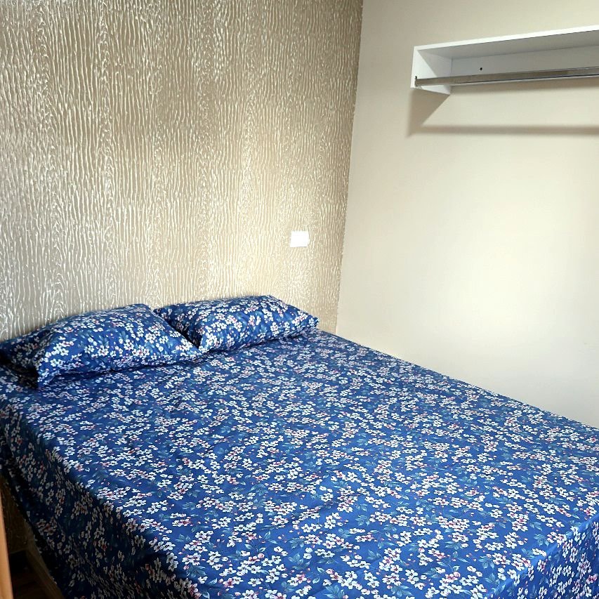 Quarto de casal do Hotel Costa com colcha azul e cabeceira de papel de parede